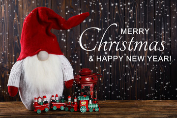 Merry Christmas and Happy New Year greeting card. Cute gnome and other festive decor on wooden table