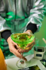 Vibrant lime cocktail presentation, Bartender displays colorful drink elegantly, Focus on bartender presenting vibrant green drink in stylish setting with soft lighting