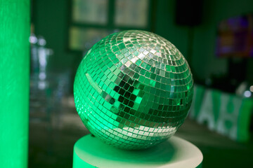 Green illuminated reflective mosaic, Velvet table illuminated by radiant glowing ball, Celebratory party centerpiece with luminous mosaic mirror ball and velvet table