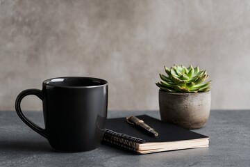 Matte black beverage container rests beside a small potted succulent and writing pad