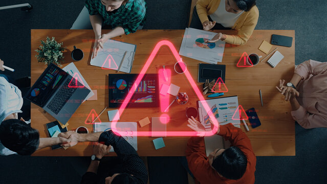 A group of professionals engages in a collaborative meeting analyzing data with charts. An overlay of a warning icon emphasizes potential risks in strategy development. Trope