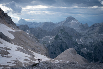 Man standing in front of beautiful alpine landscape with mountains and ridges during sunset,Slovenia