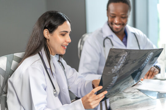 Two professional doctors analyzing an x-ray image together in a modern clinic office, discussing diagnosis and medical treatment, representing teamwork and digital healthcare communication.