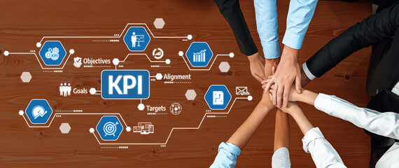 A top-down view of hands coming together on a table with KPI metrics and icons, symbolizing...