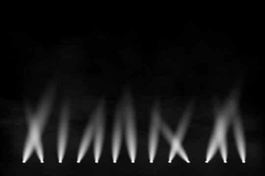 White stage spotlights shining through smoke and fog on dark black background