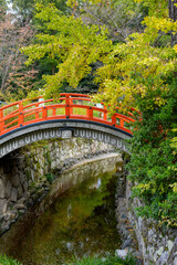 朱塗りの和風橋と川に映る緑の風景
