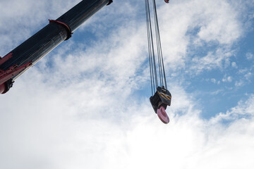 Crane machine to lift heavy object during it preparing to hook down, with day sky as blur background. Industrial operation scene and equipment object.