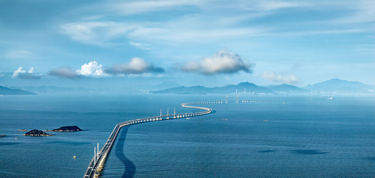 High angle telephoto view of the famous long sea-crossing bridge connecting islands over the blue ocean under a partly cloudy sky.