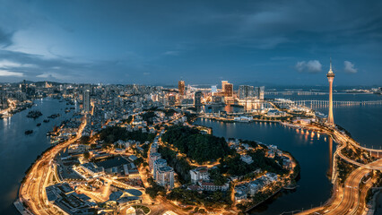 Panoramic view of the illuminated city skyline with a famous tower and waterfront landscape at night in Macau.