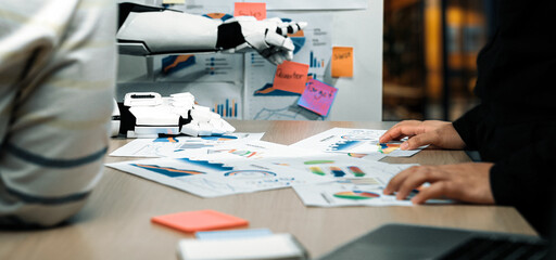 A modern office environment featuring a robotic arm engaged in analyzing various business charts...