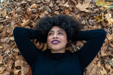 Calm black woman contemplating in autumn leaves