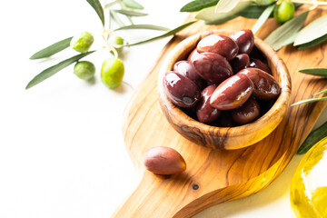 Olives in the bowl at white table.