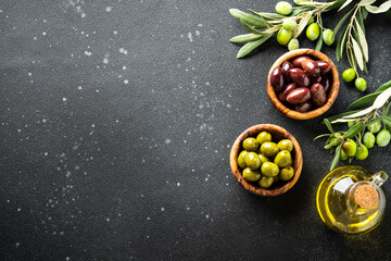 Olives in wooden bowls and Olive oil in the bottle at white table.