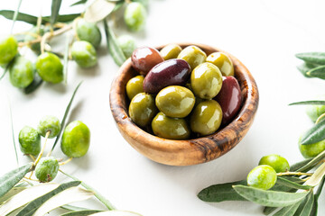 Olives in the bowl at white table.
