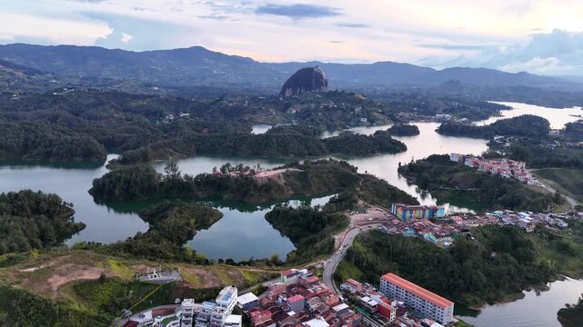 A wide, high-angle aerial performs a quarter circle around the distant El Pe&ntilde;&oacute;n de Guatap&eacute; monolith and the expansive, complex reservoir in Guatap&eacute;, Colombia