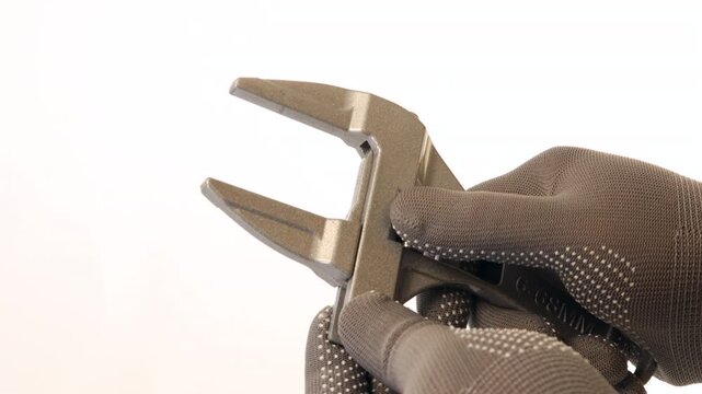 An adjustable wrench and caliper tool in gloved hands showcasing metallic finish, open jaws, and precision against plain background for optimal functionality and design