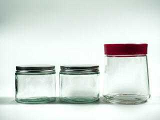Three clean glass jars with metal and red lids for food storage, preserving, or crafting, showcasing organization and freshness.