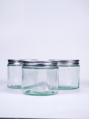 Three clean glass jars with silver lids arranged on a white surface, perfect for home organization or product packaging.