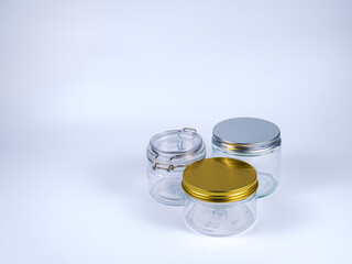 Three versatile glass jars with metallic and clip-top lids, perfect for food storage, crafting, or elegant product packaging presentation