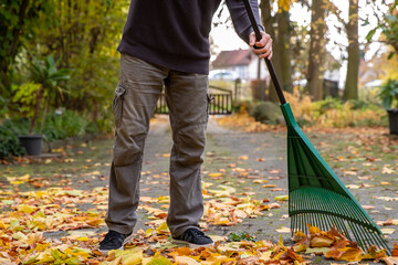 Laub zu Hause auf dem Hof im Herbst zusammenfegen.