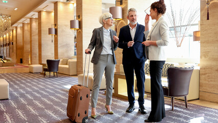 Business people traveling and networking in modern hotel lobby, discussing work trip plans and collaborations © PeopleVideos