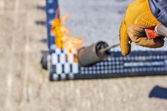 Repairing a soft roof with a fusible material using a gas torch and a propane gas cylinder