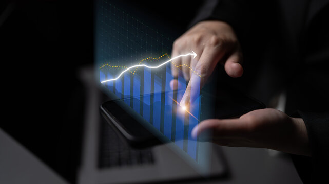 A business professional interacts with a smartphone displaying dynamic graph trends, illustrating financial growth in a modern office. The sleek design emphasizes digital innovation. Impute
