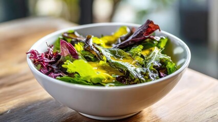 A white bowl of mixed leafy greens salad with dressing on a wooden table. Concept Fresh greens salad, White bowl presentation, Wooden table setting, Drizzled dressing, Healthy meal styling