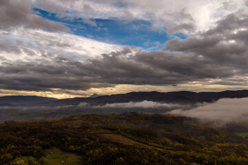 Scenic mountain landscape with clouds and fog during sunset over a valley