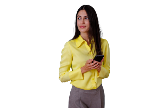 Young businesswoman with dark hair and yellow shirt holding a mobile phone, engaging with technology, looking sideways