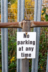 No parking at any time warning sign on fence