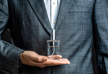 Men perfume in the hand on suit background. Fragrance smell. Men perfumes. Fashion cologne bottle....