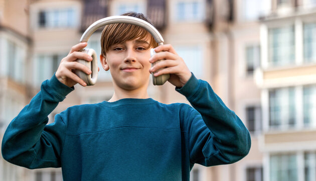 Young man with headphones listening to music in the city streets. Teenage boy with headphones