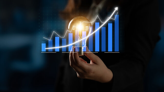 A business professional holds a light bulb, symbolizing innovation, against a backdrop of a rising growth chart, representing financial success and creative ideas. Impute - Powered by Adobe