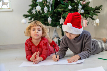 Children writing letters to Santa Claus Saint Nicholas under the Christmas tree