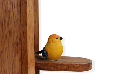 A small yellow bird statue decorated on a wooden pole on isolated background