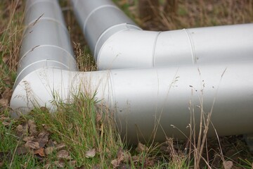 Two industrial pipes installed on the ground in nature. 