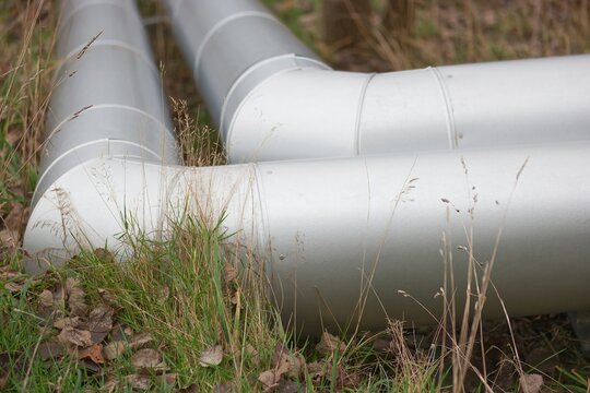 Two industrial pipes installed on the ground in nature.