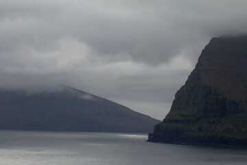 Misty mountain rising above the sea in the Faroe Islands, capturing the wild spirit of Nordic travel and hiking adventures.