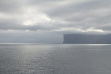 Misty mountain rising above the sea in the Faroe Islands, capturing the wild spirit of Nordic travel and hiking adventures.