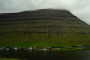 Peaceful view of Kunoy village surrounded by steep mountains and the North Atlantic — a hidden gem for hikers and travelers in the Faroe Islands.
