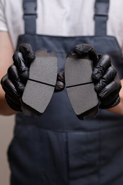 Mechanic holds new brake pads, assessing flawless brake components for safety, large plan. Concept of replacing brake pads, car maintenance. Vertical