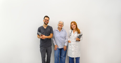 Portrait of happy ophthalmologist with senior woman standing together against white background in...