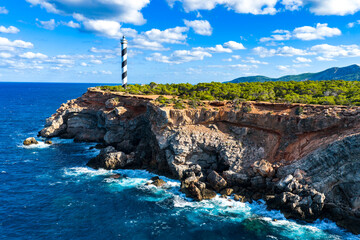 Aerial View of the Striped Moscarter Lighthouse (Far de sa Punta des Moscarter) on the Rugged Northern Cliffs of Ibiza, Spain