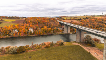 Scenic view of highway bridge across Danube towards Regensburg in golden autumn landscape of Bavaria surrounded by trees and water