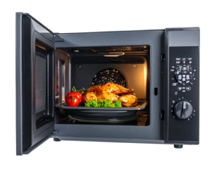 A cooked chicken, tomato, and greens inside a microwave with the door partially open, casting a warm light