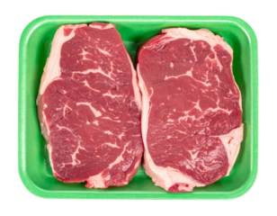 Raw beef ribeye steaks with beautiful marbling in green supermarket foam tray on white background