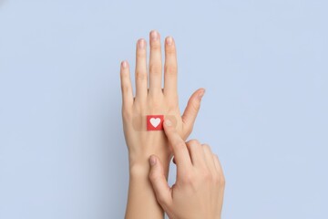 Hand Applying Heart Shaped Bandage on Wrist