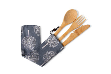 Reusable, natural bamboo fork, spoon, and serrated knife set pulled out of a gray fabric travel pouch with a white tree pattern, isolated on white