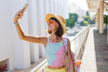 Stylish tourist travels around Tel Aviv and takes photos of sights on her smartphone. Blogger...